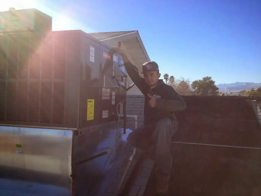 HVAC technician performing Air Duct Cleaning on a rooftop unit in Overland